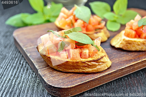 Image of Bruschetta with tomato and basil on wooden board