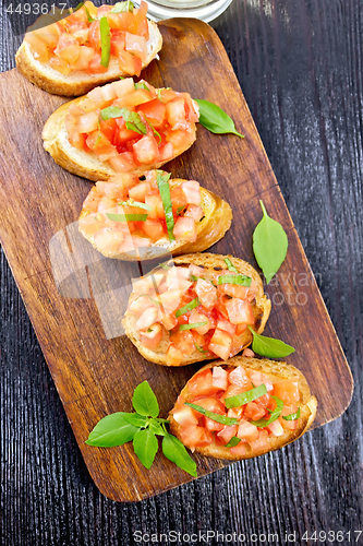 Image of Bruschetta with tomato and basil on dark board top