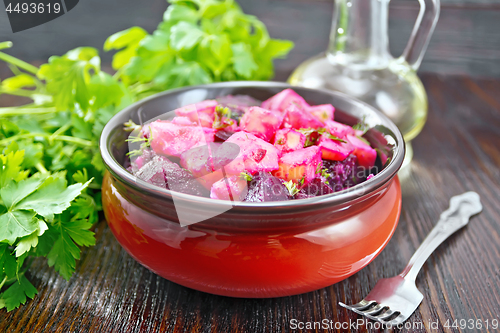 Image of Salad of beets and potatoes with oil in bowl on dark board