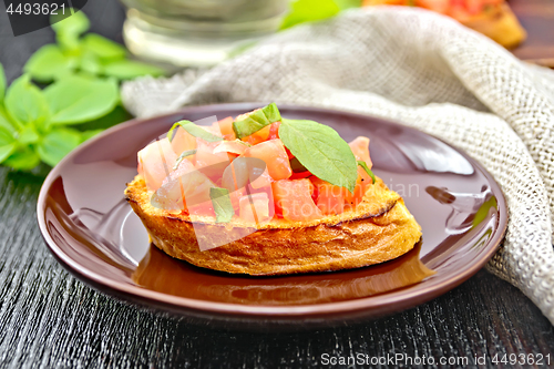 Image of Bruschetta with tomato and basil in brown plate on board