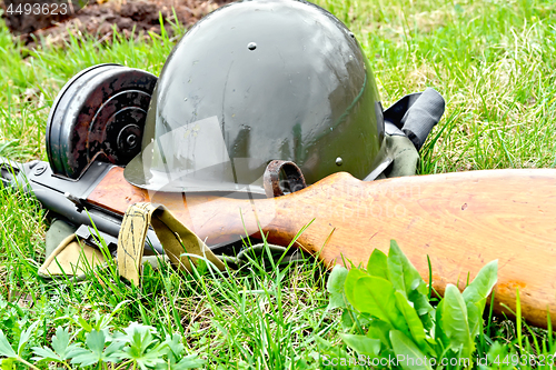 Image of Helmet and submachine gun on grass