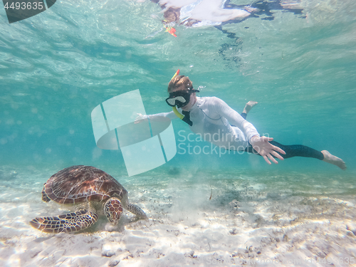 Image of Woman on vacations wearing snokeling mask swimming with sea turtle in turquoise blue water of Gili islands, Indonesia. Underwater photo.