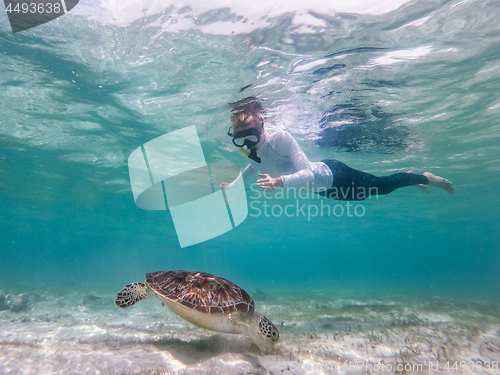 Image of Woman on vacations wearing snokeling mask swimming with sea turtle in turquoise blue water of Gili islands, Indonesia. Underwater photo.