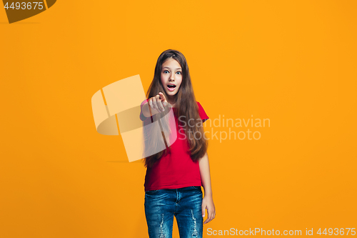 Image of The happy teen girl pointing to you, half length closeup portrait on orange background.