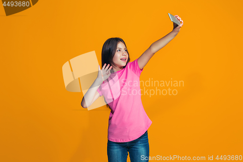 Image of The happy teen girl standing and smiling against orange background.