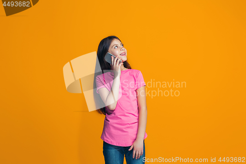 Image of The happy teen girl standing and smiling against orange background.