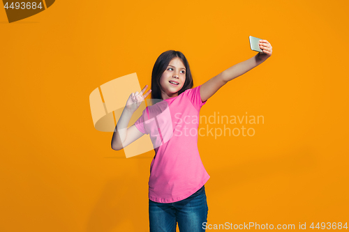 Image of The happy teen girl standing and smiling against orange background.