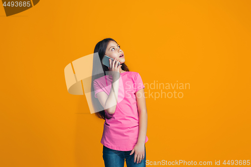 Image of The happy teen girl standing and smiling against orange background.