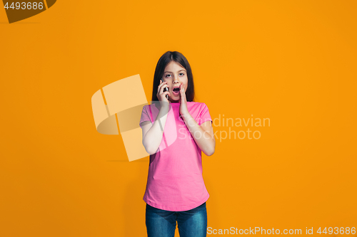 Image of The happy teen girl standing and smiling against orange background.