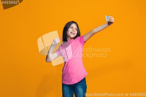 Image of The happy teen girl standing and smiling against orange background.