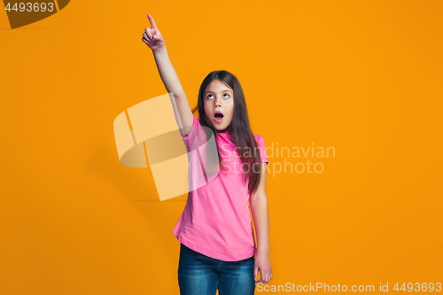 Image of Beautiful teen girl looking suprised isolated on orange