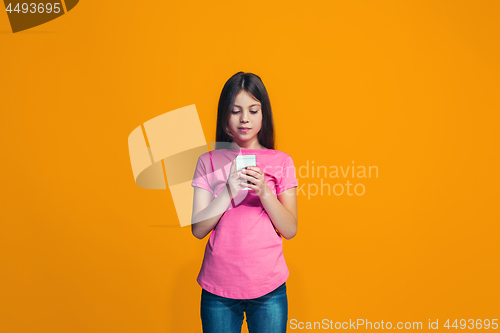 Image of The happy teen girl standing and smiling against orange background.