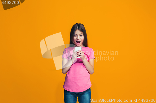 Image of The happy teen girl standing and smiling against orange background.