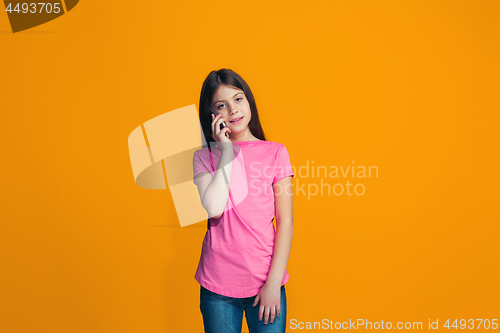 Image of The happy teen girl standing and smiling against orange background.