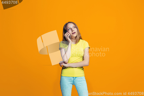 Image of The happy teen girl standing and smiling against orange background.