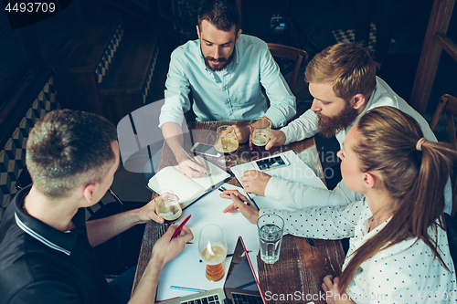 Image of Young cheerful people smile and gesture while relaxing in pub.