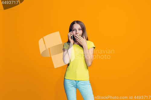 Image of The happy teen girl standing and smiling against orange background.