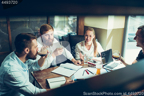 Image of Young cheerful people smile and gesture while relaxing in pub.