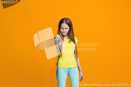 Image of The happy teen girl pointing to you, half length closeup portrait on orange background.