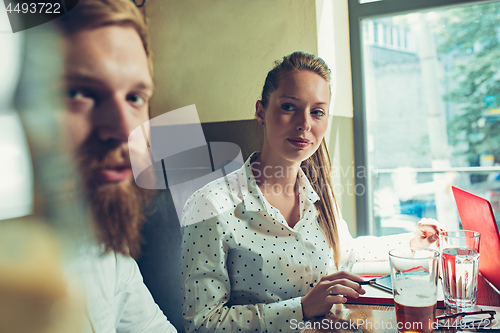 Image of Young cheerful people smile and gesture while relaxing in pub.