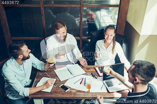 Image of Young cheerful people smile and gesture while relaxing in pub.