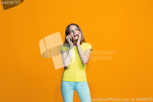 Image of The happy teen girl standing and smiling against orange background.