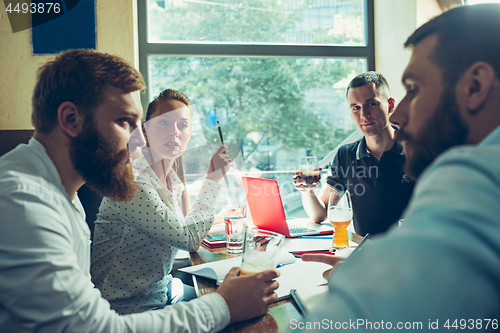 Image of Young cheerful people smile and gesture while relaxing in pub.