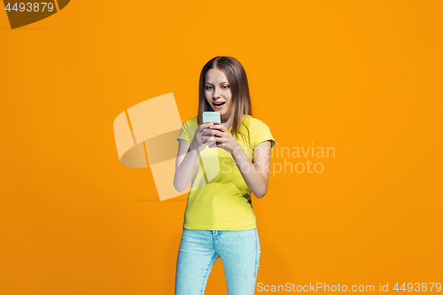 Image of The happy teen girl standing and smiling against orange background.