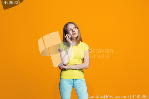 Image of The happy teen girl standing and smiling against orange background.