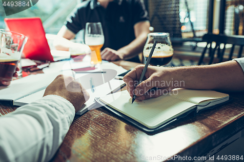 Image of Young cheerful people smile and gesture while relaxing in pub.