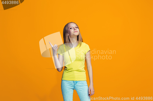 Image of The happy teen girl standing and smiling against orange background.