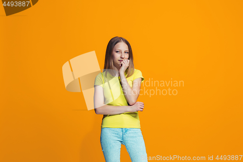 Image of Beautiful teen girl looking suprised and bewildered isolated on orange