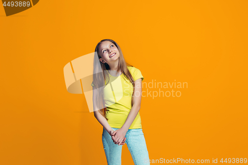 Image of The happy teen girl standing and smiling against pink background.