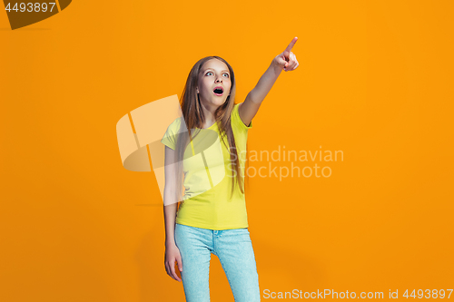 Image of Beautiful teen girl looking suprised isolated on orange