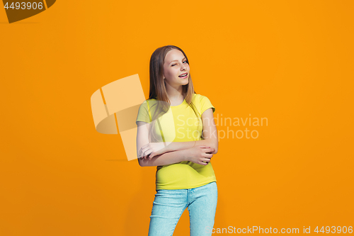 Image of The happy teen girl standing and smiling against orange background.