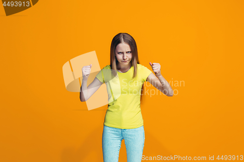 Image of Portrait of angry teen girl on a orange studio background