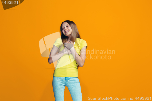 Image of The happy teen girl standing and smiling against orange background.