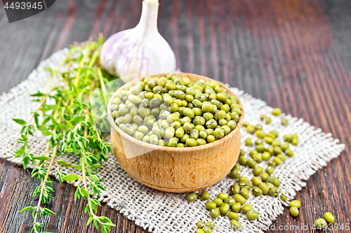 Image of Mung beans in wooden bowl with thyme on table