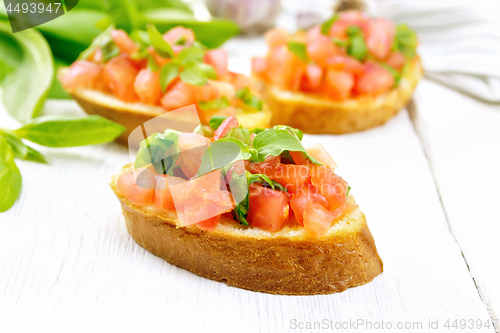 Image of Bruschetta with tomato and spinach on light wooden board