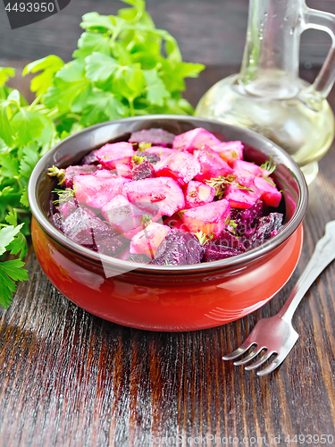 Image of Salad of beets and potatoes with oil in bowl on board