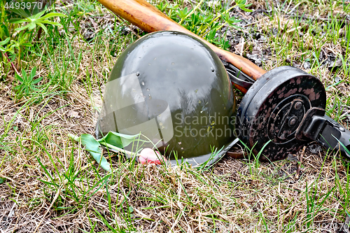 Image of Helmet and submachine gun with tulip on grass