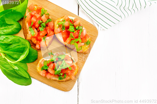 Image of Bruschetta with tomato and spinach on light board top