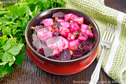 Image of Salad of beets and potatoes with napkin in bowl on board