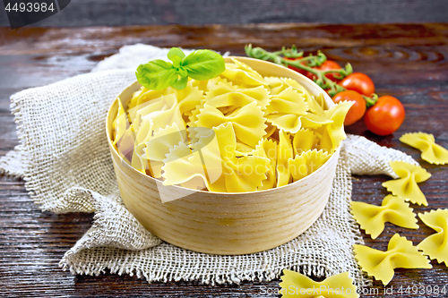 Image of Farfalle in bark box with basil on dark board