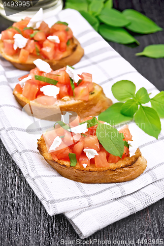 Image of Bruschetta with tomato and feta on dark board