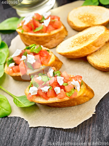 Image of Bruschetta with tomato and cheese on wooden board