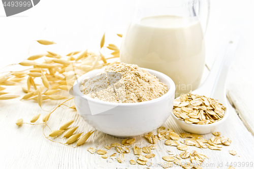 Image of Flour oat in bowl with milk on light wooden board