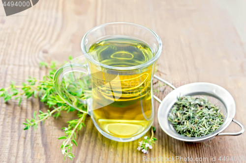 Image of Tea of thyme in mug with strainer on old board