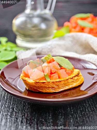 Image of Bruschetta with tomato and basil in plate on dark board