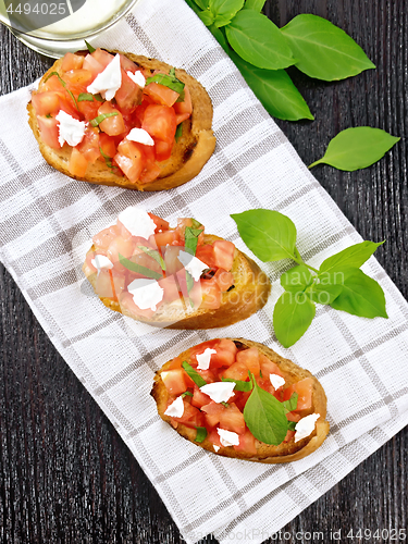 Image of Bruschetta with tomato and feta on dark board top